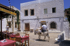 Man riding on small white Donkey in a village Greece Europe